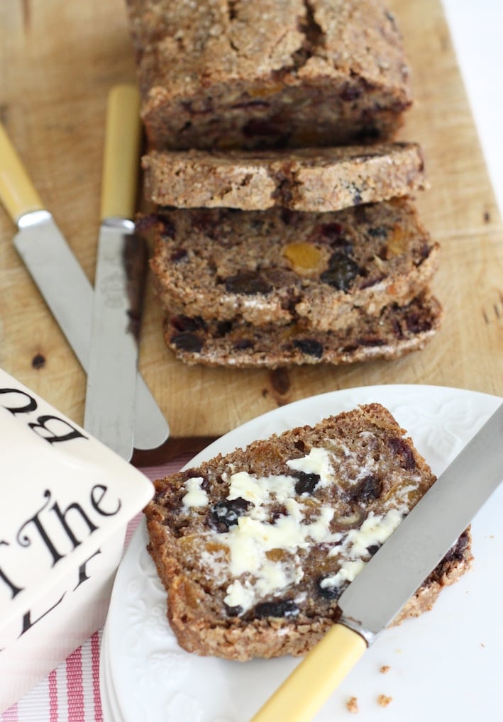 Earl Grey Fruit Loaf sliced on a wooden board with 2 knives and a butter dish