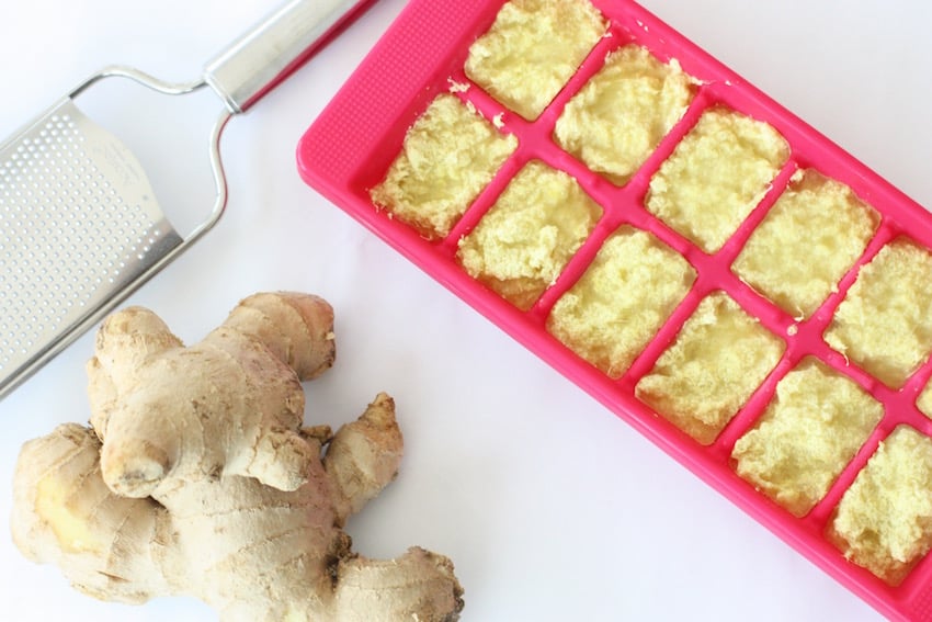 frozen ginger in a pink ice cube tray next to a piece of fresh ginger
