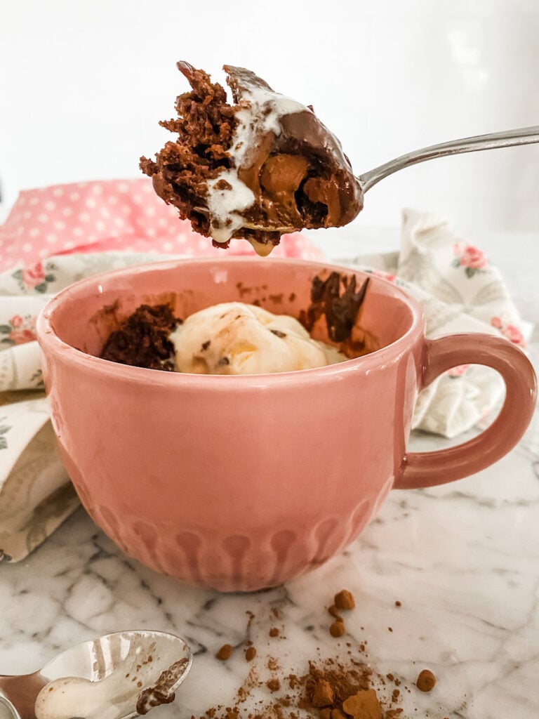 Chocolate mug cake in a pink mug with vanilla ice cream and a spoon