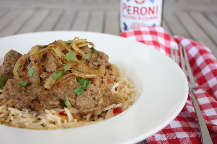 Lamb, Tomato and Coconut Curry in a white dish with a red gingham napkin