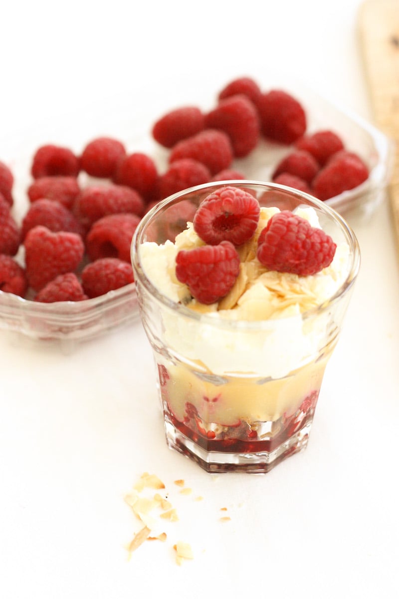 An Easy Lemon and Raspberry Cheesecake in a glass in front of a punnet of raspberries