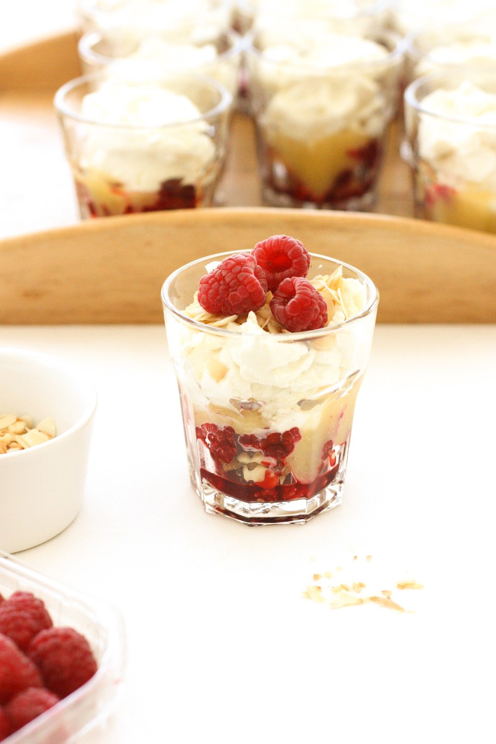 An Easy Lemon and Raspberry Cheesecake in a glass in front of a wooden tray