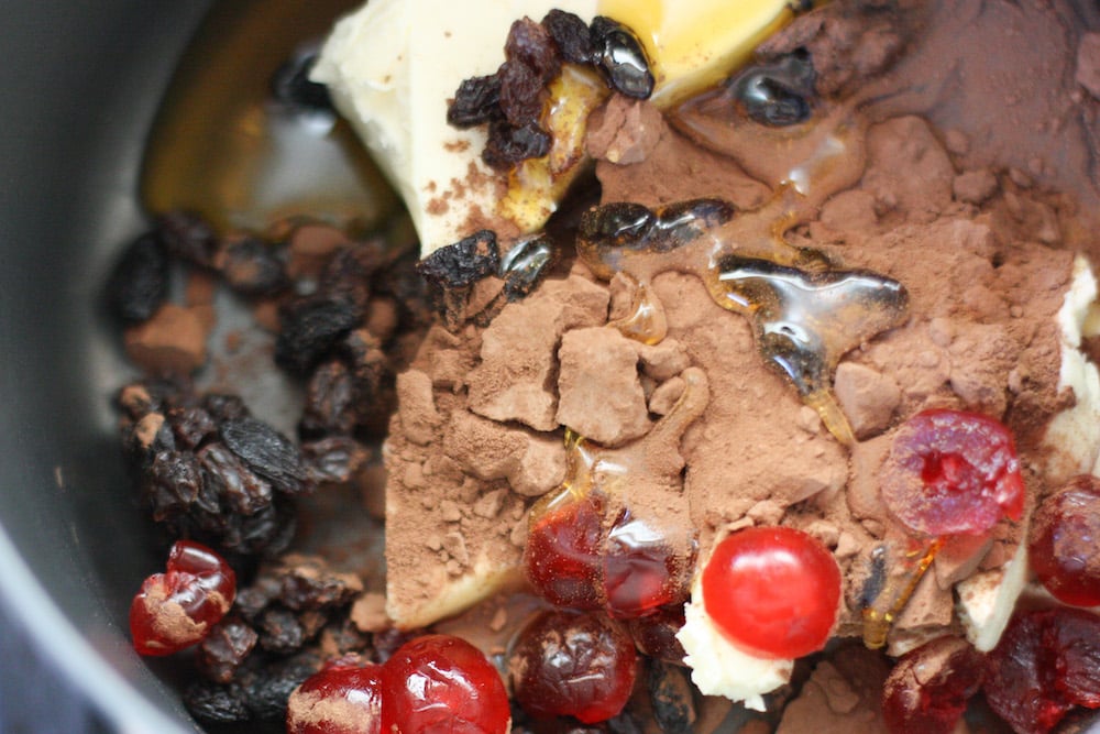Ingredients in a pan - butter, golden syrup, cocoa, raisins and cherries
