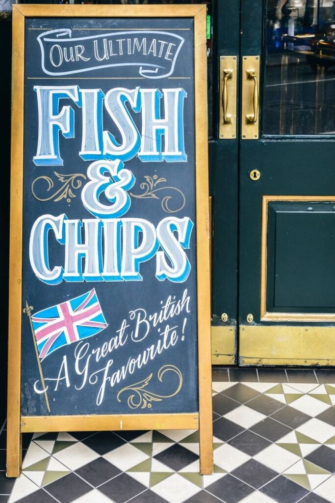 A blackboard advertising fish and chips infant of dark green doors