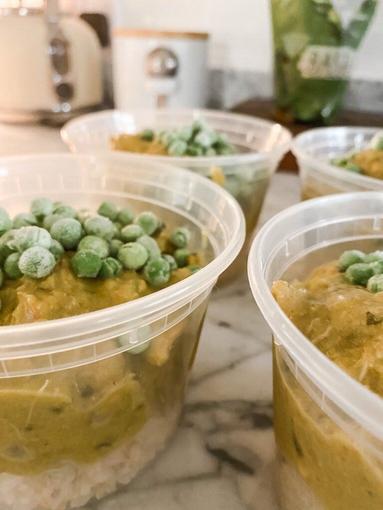 Four plastic pots of chicken curry, rice and peas, ready to go in the freezer