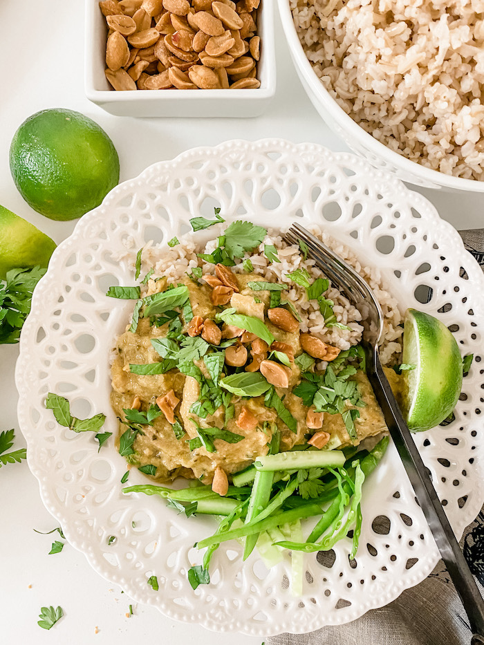 Slow Cooker Lemongrass and Coconut Chicken Curry in a flat white bowl with lots of herbs to garnish and a fork