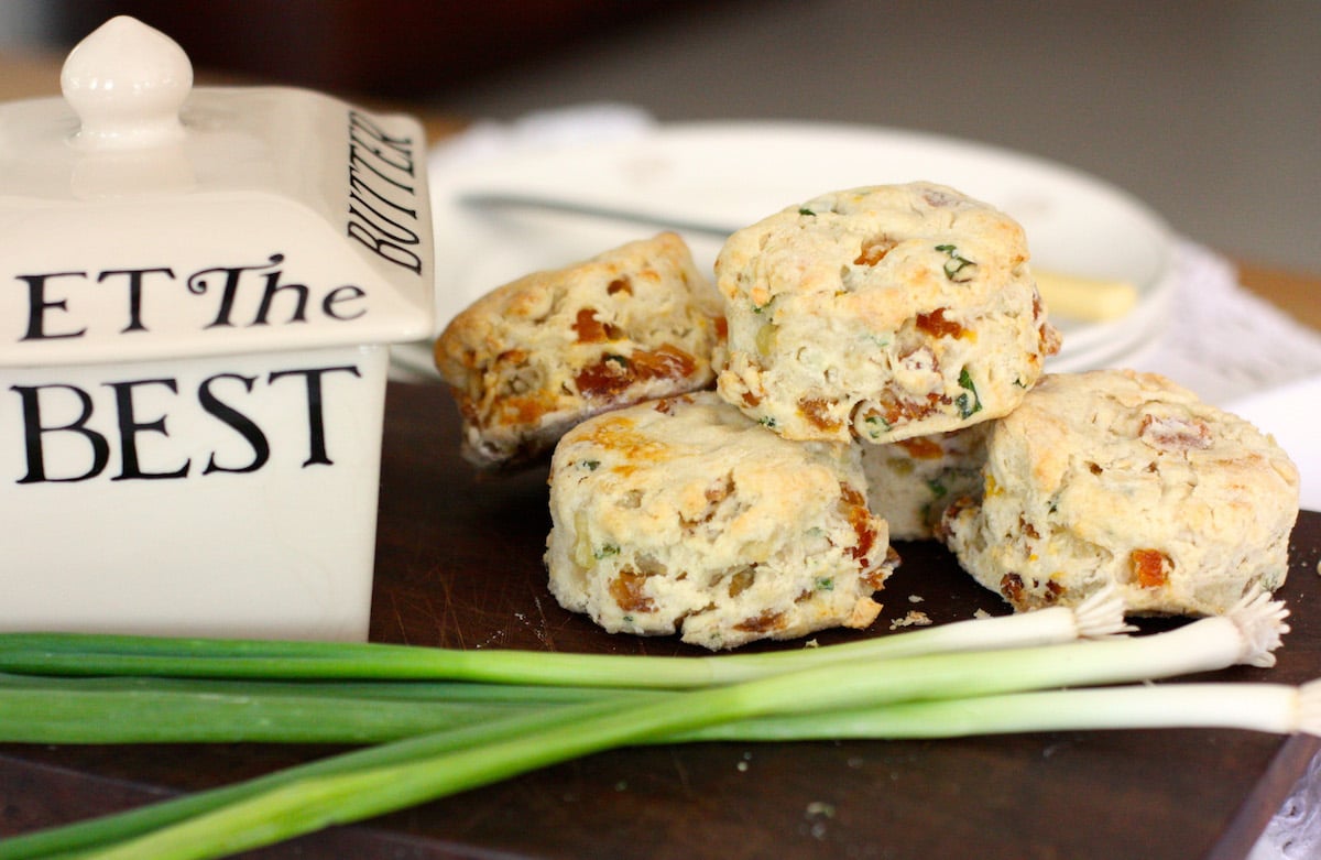 White Stilton and Apricot Scones on a board with spring onions and a butter dish