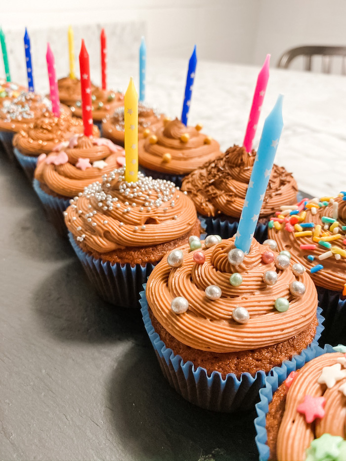 Two rows of chocolate cupcakes with candles