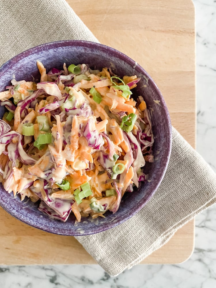Easy Classic Homemade Coleslaw in a purple bowl on a wooden board