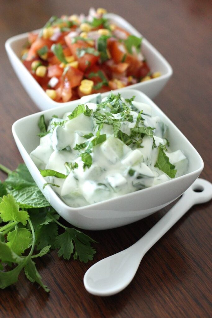 Raita and tomato salad in small white bowls
