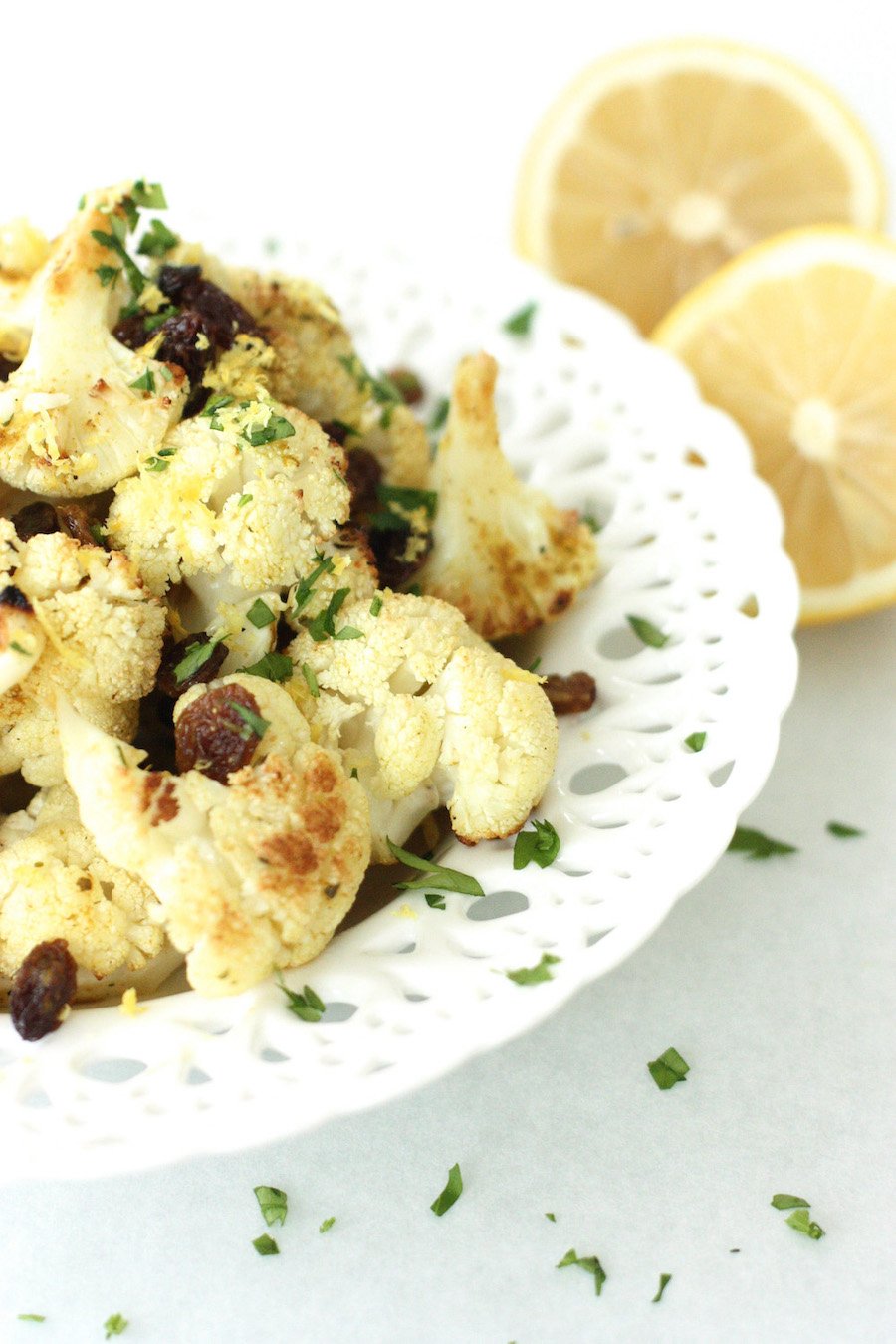 Roasted Curried Cauliflower Salad on a white dish with lemons in the background