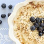 Creamy Coconut Porridge in a white fluted bowl topped with blueberries