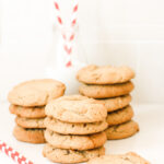 Stem ginger cookies in three piles with a bottle of milk and straws