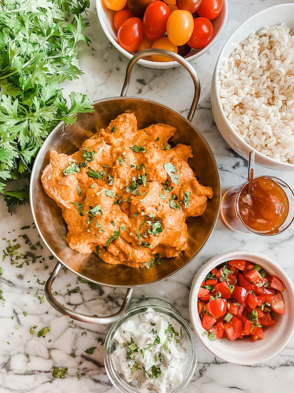 Butter Chicken in a silver dish with all the sides