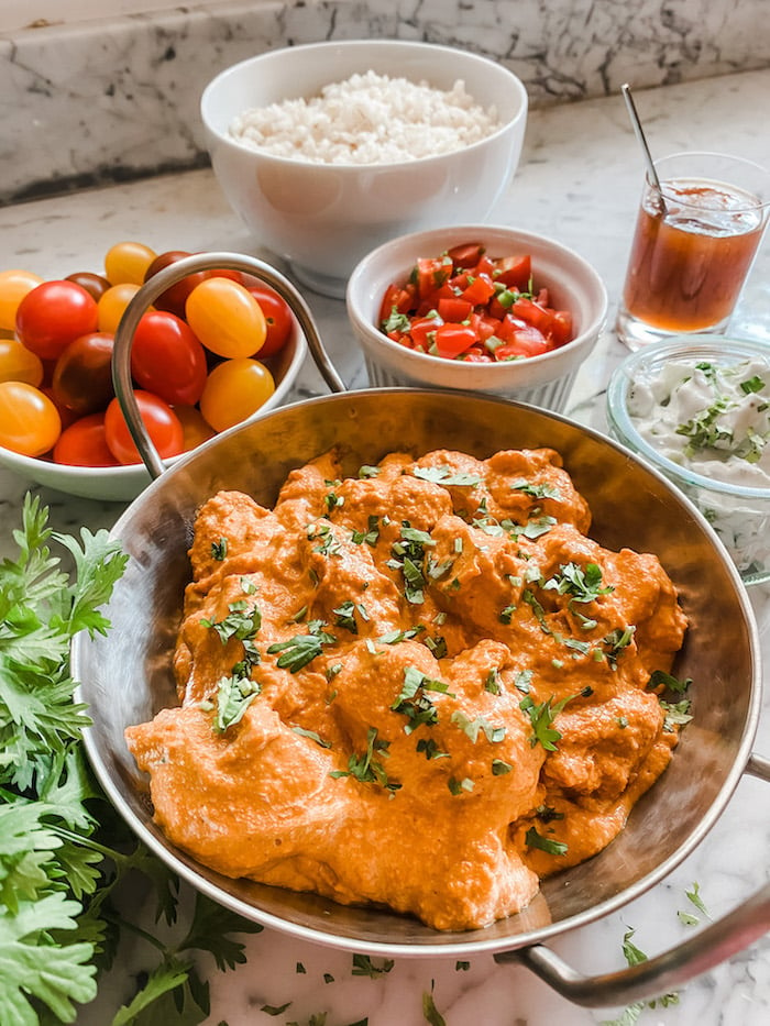 Butter Chicken in a silver dish with all the sides
