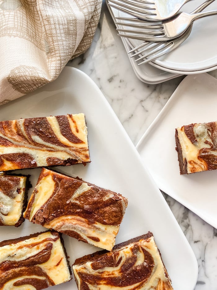 Chocolate Orange Cheesecake Brownies on white plates with a pile of forks
