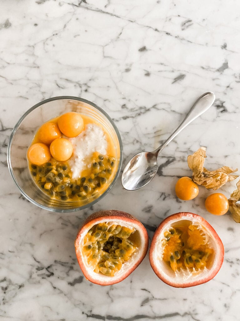 Overnight Oats in a glass dish topped with passion fruit and Cape gooseberries