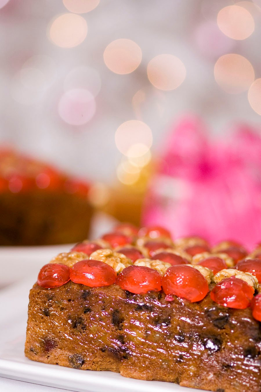 A square Christmas cake with festive lights in the background