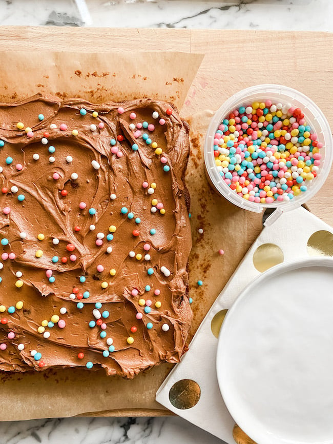 Cute Weekend Chocolate Cake with sprinkles ready to slice on a wooden board