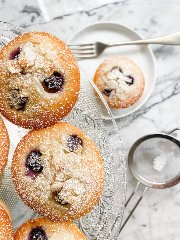 Blueberry and Lemon Friands on a glass cake stand