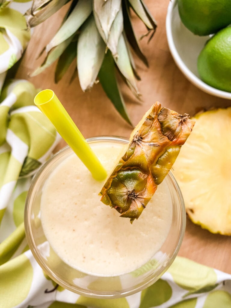Pineapple and Coconut Smoothie on a wooden board with limes and a pineapple